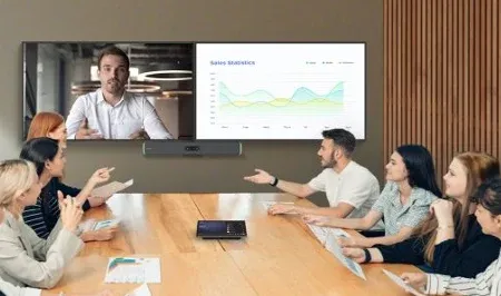 Team collaborating around a table with remote participants on screen
