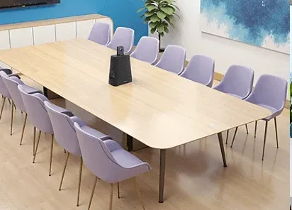 Mid-size meeting room with a wide table and a conferencing puck