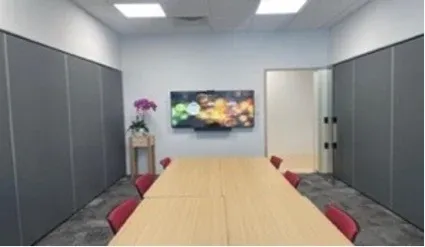 Combinable meeting room with a wall display and video bar above a long table